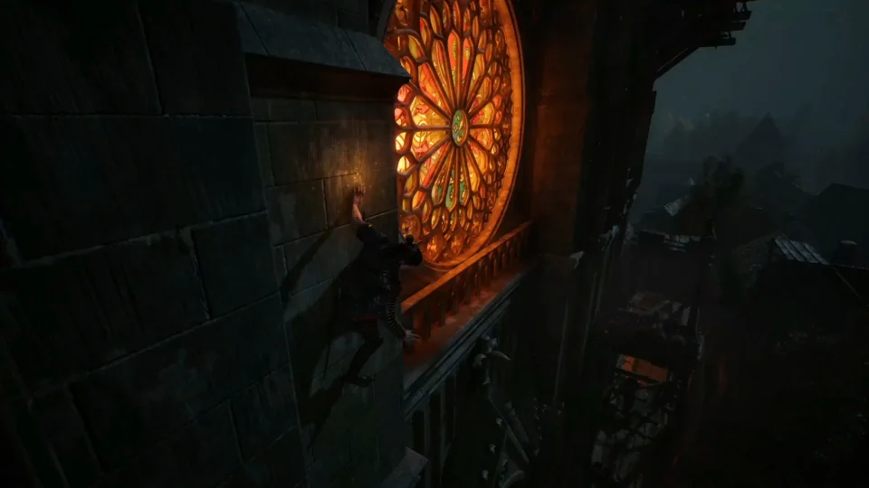 Coen moves along the side of a church tower beside a glowing circular window at night.