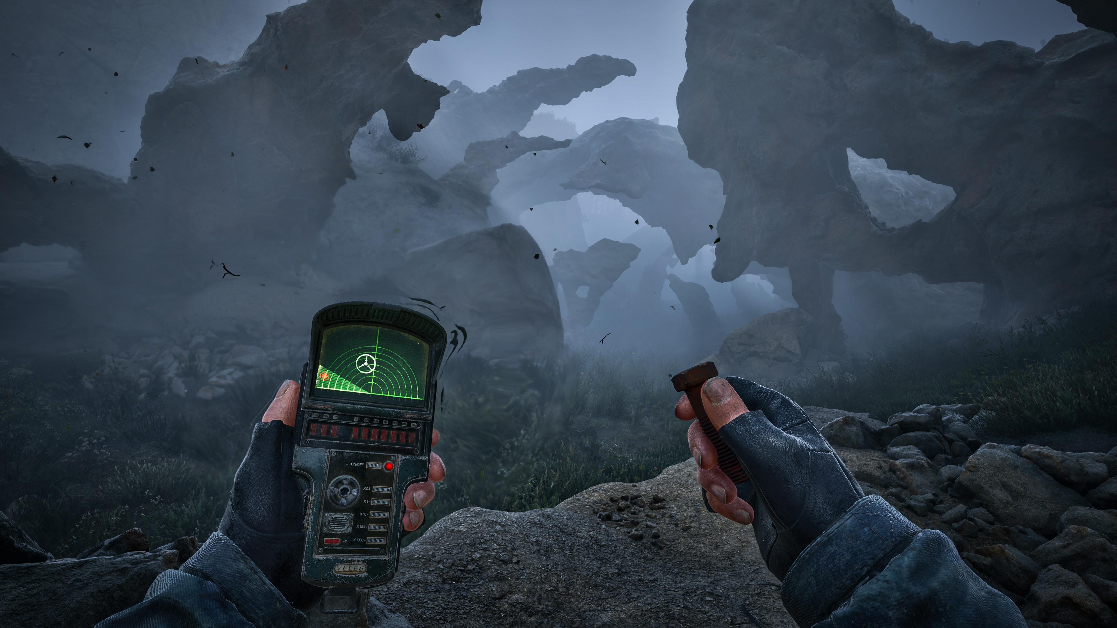 A first-person view of two gloved hands, one holding a handheld detector with a glowing green dial, the other a metal bolt, before pale rock formations rising out of heavy fog.
