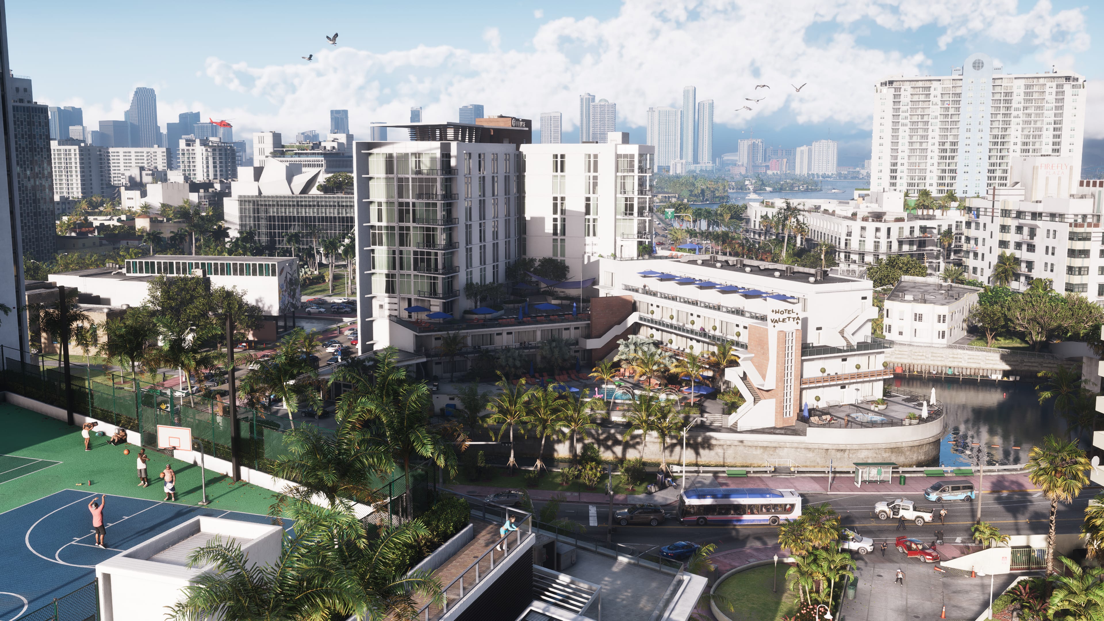 A wide daytime view over Vice City: low-rise blocks, sports courts and palm-lined streets give way to white towers on the horizon.