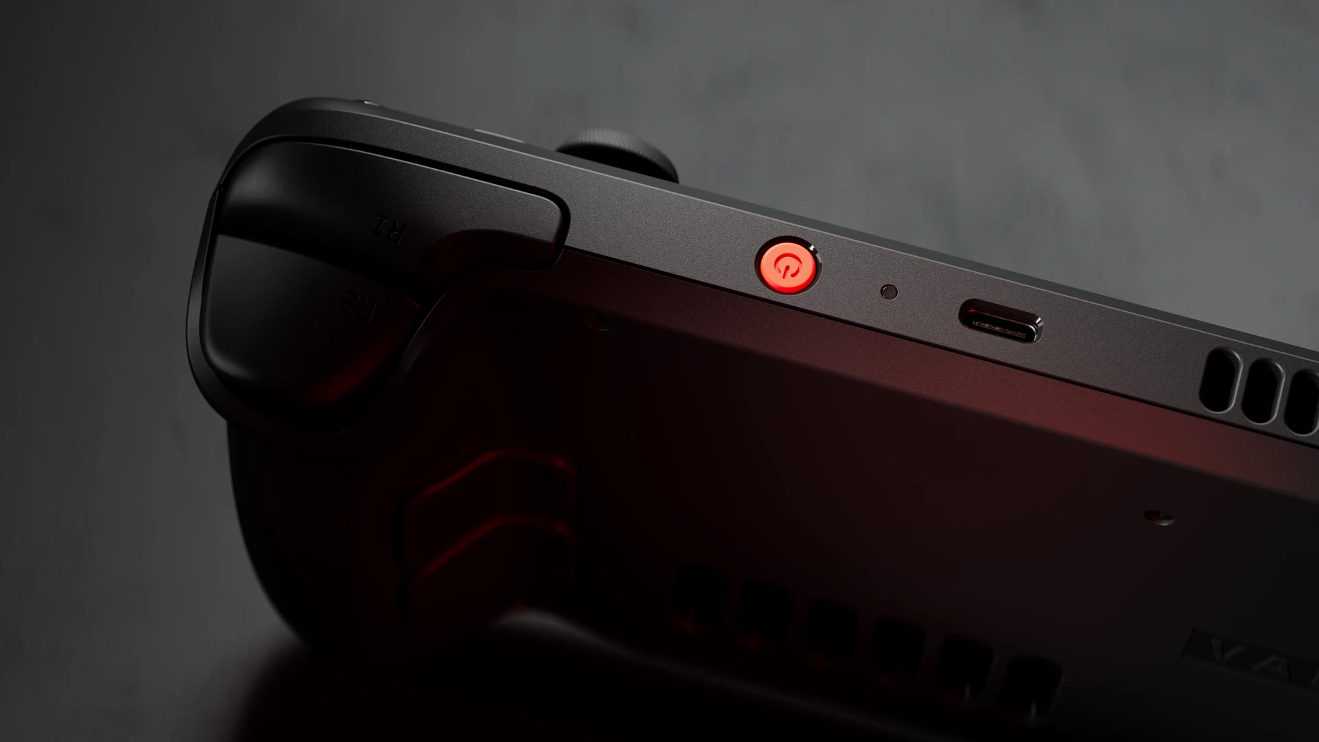 Valve render of the Steam Deck OLED from above and behind the right grip, showing the R1 bumper and R2 trigger, the orange power button, USB-C port and vent on the top edge, and part of the back shell with a rear grip button.